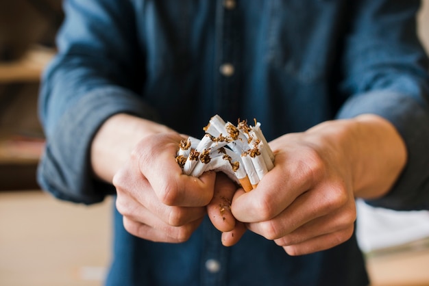 Man's hands breaking bunch of cigarettes