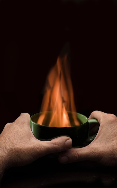 man's hands over cup with fire to warm up energy poverty