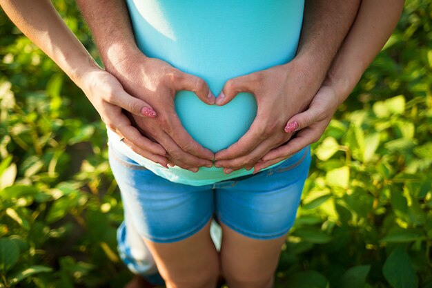 男の手は妊娠中の女性の腹を抱きしめます