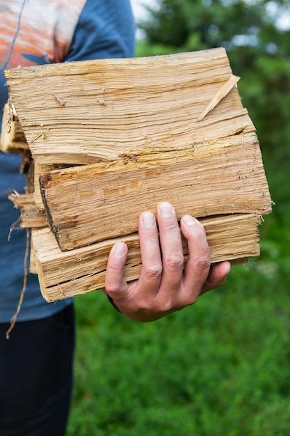 Man's hands hold firewood An unrecognizable man carries firewood to the house to light a fireplace Rustic countryside background