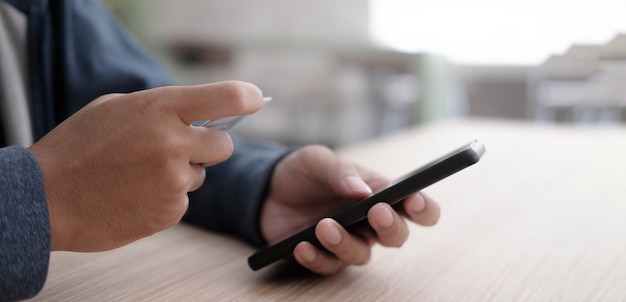 Man's hands holding a credit card and using smart phone for online shopping