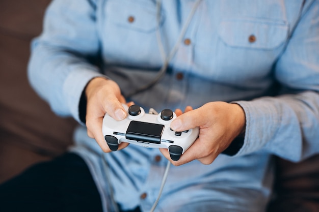 Photo man's hands holding game controller. close up. good time on weekend concept. cut view of male hands. adult man playing video games at home. casual clothes. spending time during quarantine.