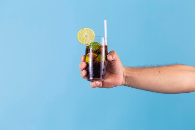 Man's hands holding a glass of coca soda