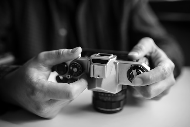 Man's hands set up retro film camera. Black and white