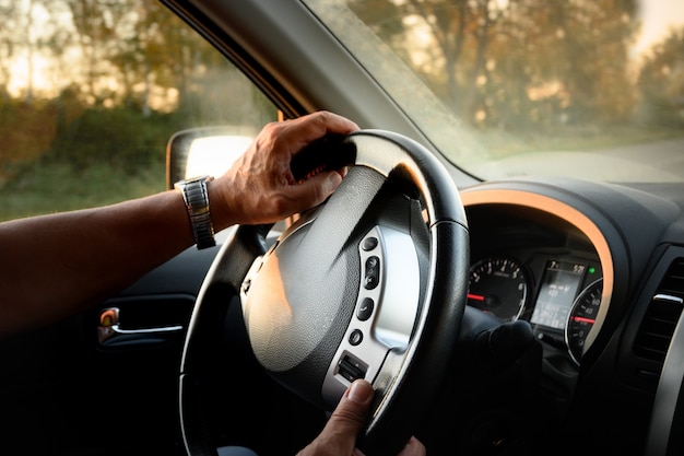 Photo man s hands on steering wheel summer road trip car towards the sunset