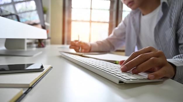 man's hands typing computer keyboard on home office workplace.