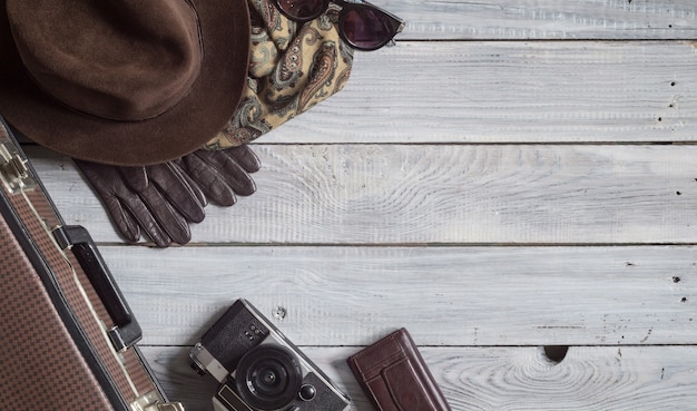 Man's hat and retro accessories for travel on a white wooden surface