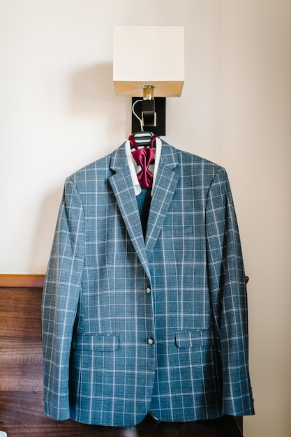 A man\'s jacket blue suit with bowtie on a hanger in the room\
stylish blue wedding