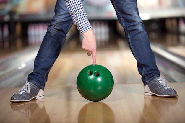 Man's legs and green bowling ball.