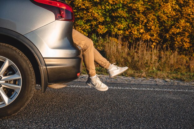 Photo man's legs sticking out of trunk of car stop for rest after long road trip