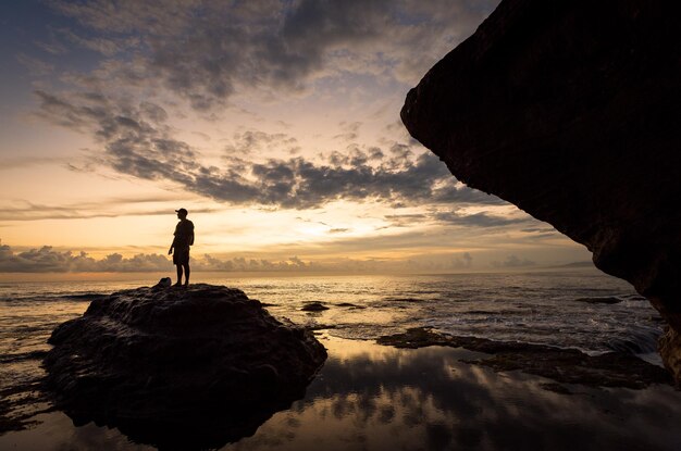 Foto sagoma dell'uomo sulla pietra vicino al tempio di tanah lot a bali, indonesia