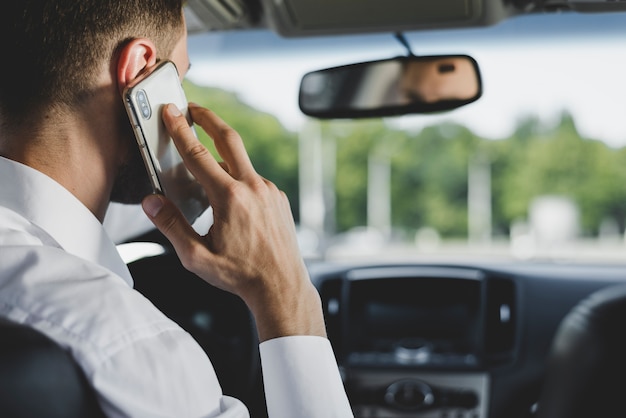 写真 車を運転している間に男がスマートフォンで話す