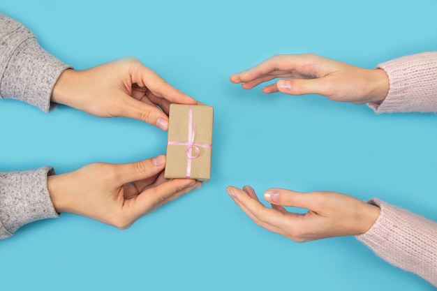 Foto le mani dell'uomo e della donna tengono la scatola con il regalo sull'azzurro.