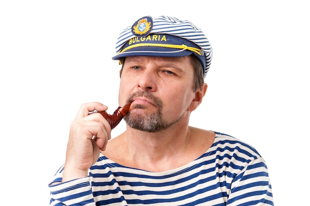 A man sailor in a cap with a smoking pipe in front of a white background