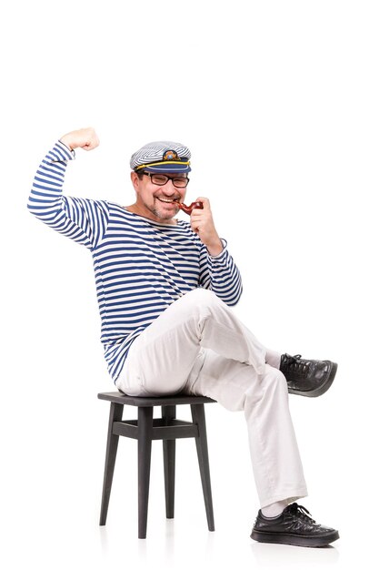 Мужчина-моряк в кепке с курительной трубкой на белом фоне