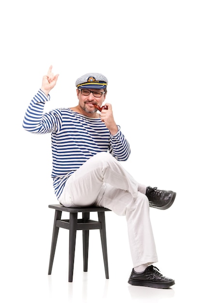Мужчина-моряк в кепке с курительной трубкой на белом фоне