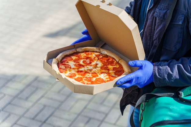 Man salami pizza leveren in kartonnen doos met veiligheidsmaatregelen