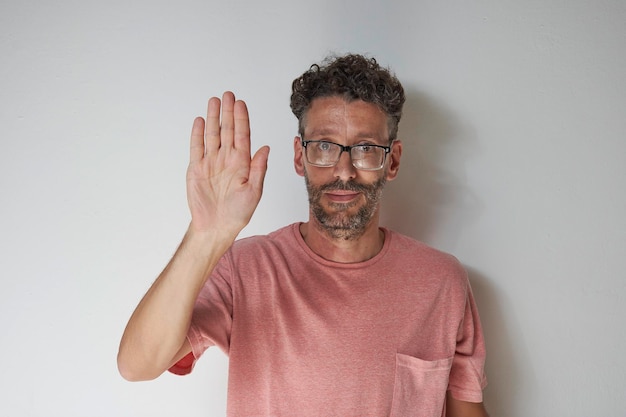 Man in salmon shirt raising hand on white background