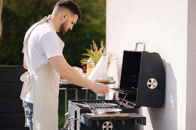 Man salted food in frying pan and prepare meal outdoor on bbq grill