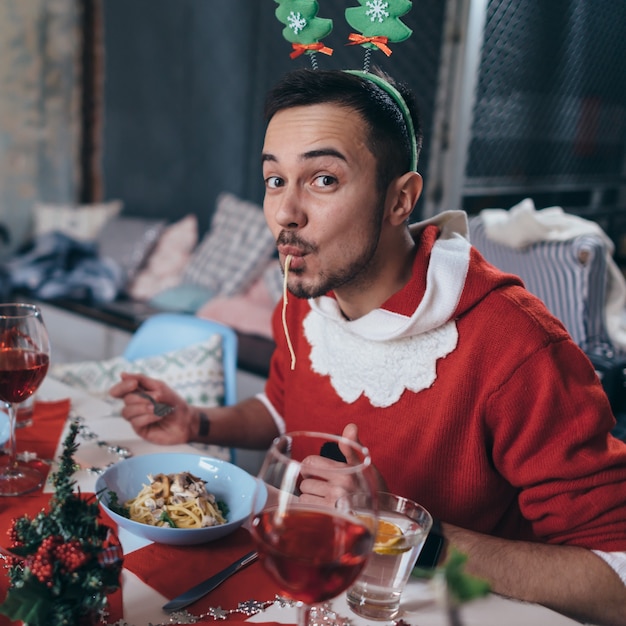 Man in Santa Claus costume eating pasta, spaghetti.