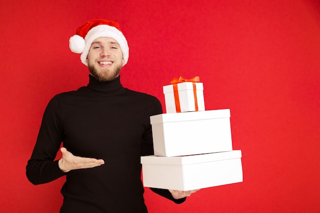 A man in a Santa Claus hat holds Christmas gift boxes