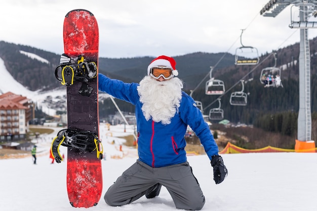 A man in a santa hat with a snowboard at a ski resort