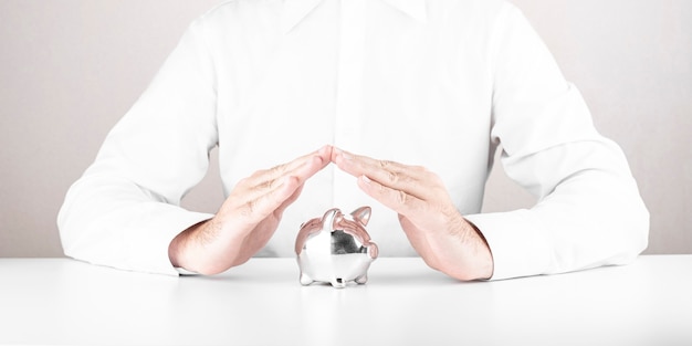 Man saving piggy bank with his hands. Concept of Finance, crisis and saving money,