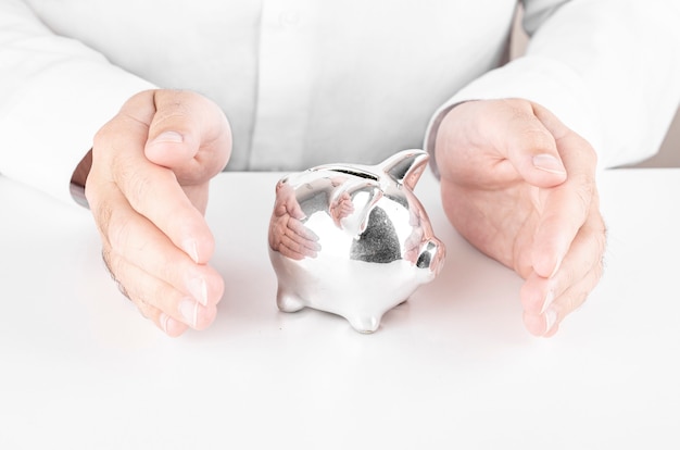 Man saving piggy bank with his hands