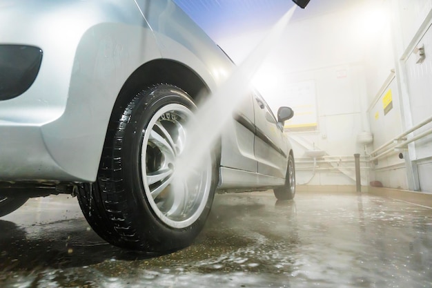 Man schoonmaak voertuig met hogedruk water spray of jet Car wash details wassen van het achterwiel van een auto