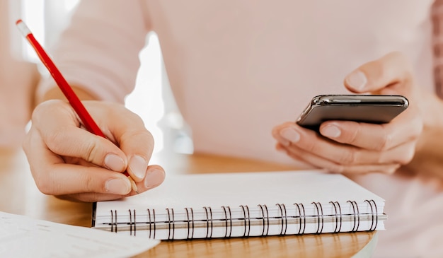 Man schrijft bedrijfsinformatie in notitieblok op werkplek op kantoor met smartphone