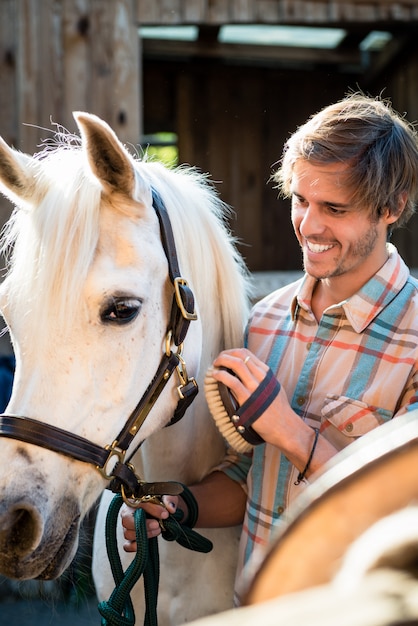 Man schrobben wit paard