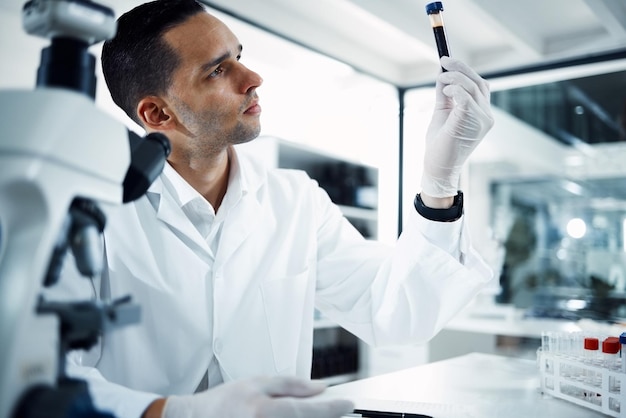 Foto scienziato uomo e analisi del campione di sangue in provetta dna e esperimento scientifico in laboratorio medico maschio con guanti studia liquido con innovazione scientifica forense e ricerca medica
