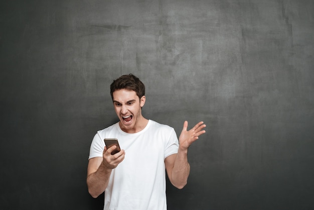 Man screaming at phone . Isolated dark wall