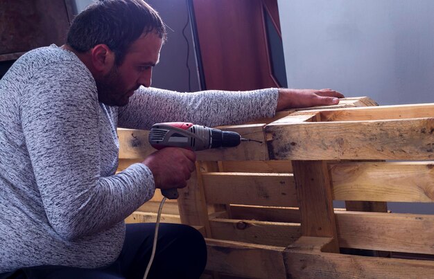 Photo man screwing a wood plate by wireless drill