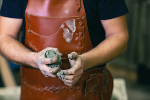 Man sculptor dressed leather apron with clay in hands Statue craft creation workshop
