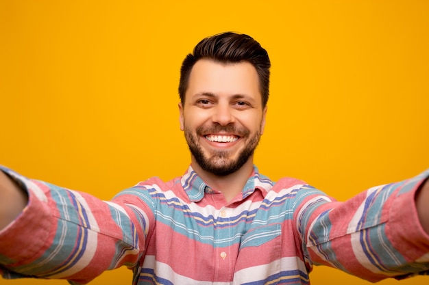 man selfie maken en staande op een oranje achtergrond.