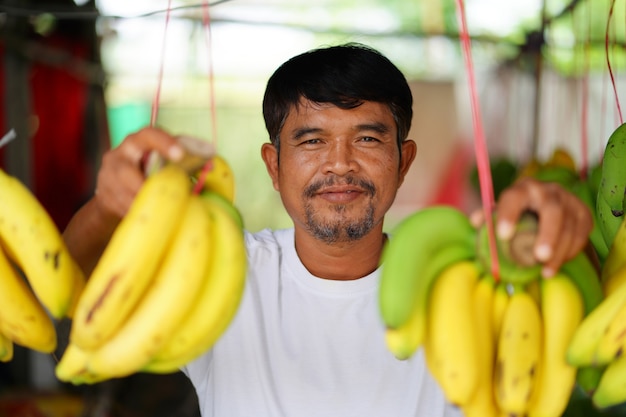 タイの地元市場で黄色いバナナを売っている男