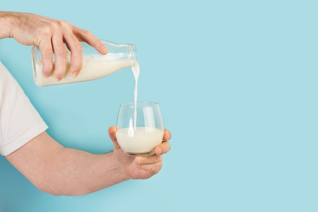 Man serveert een glas melk op een lichtblauwe muur