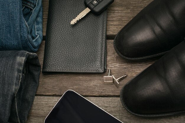 Man set voor de dag van de portefeuille, jeans, smartphone en auto sleutel op een houten bord.