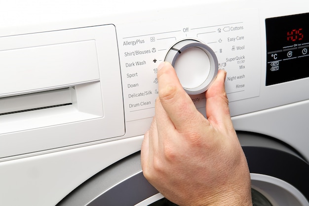 The man sets the program and turns on the washing machine.