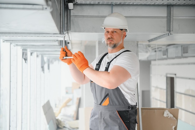 Man setting up ventilation system indoors A male worker installs air ventilation pipes in a new office building