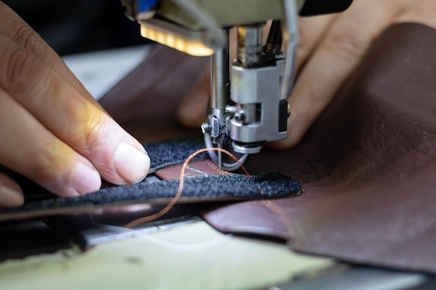 초점 에 있는 신발 바느질 기계 에서 신발 을 만들기 위해 가죽 을 바느질 하는 사람