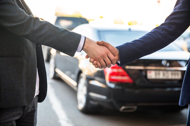Photo man shaking hands with client in car dealership