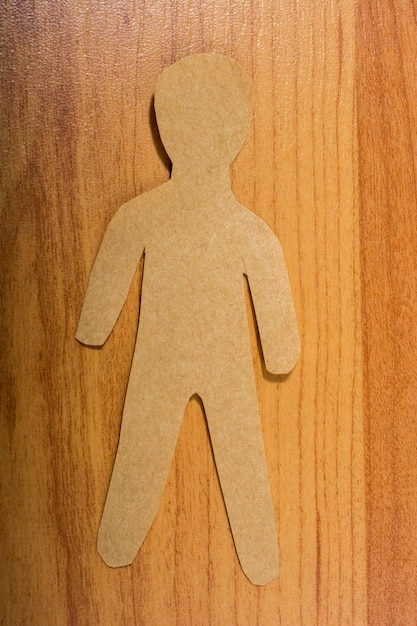 Man shape cut out of paper on wooden texture