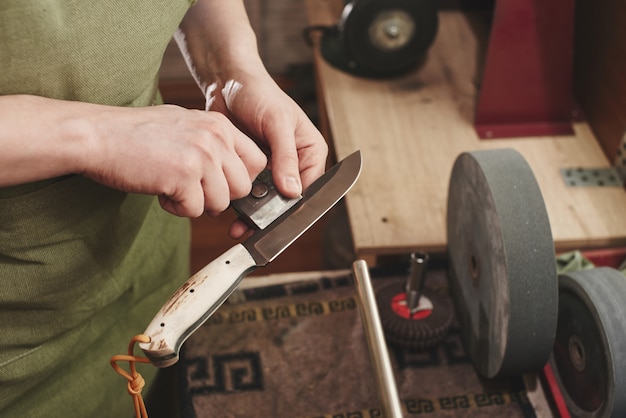 Uomo affilare un coltello in officina