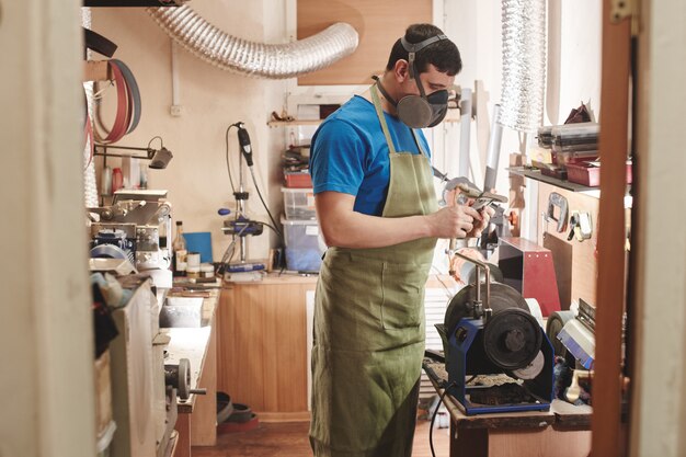 Uomo affilare un coltello in officina