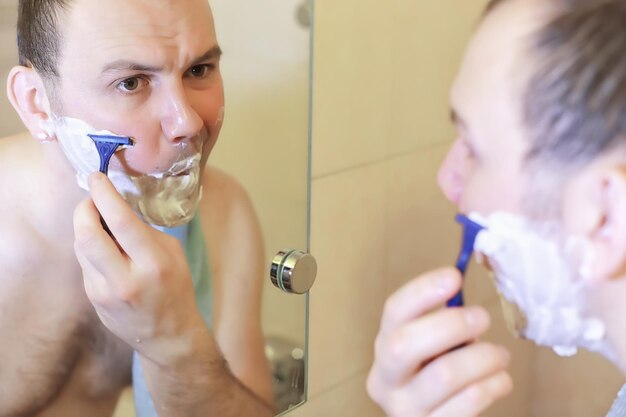 A man shaves in the bathroom in the morning before work