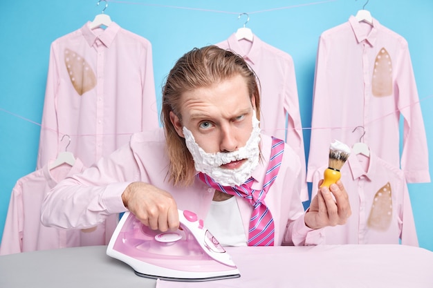 man shaves dresses up busy ironing outfit to wear uses appliance undergoes regular morning routines prepares for formal meeting wants to have perfect look