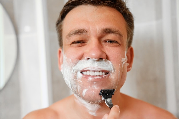 A man shaves his face with a safety razor