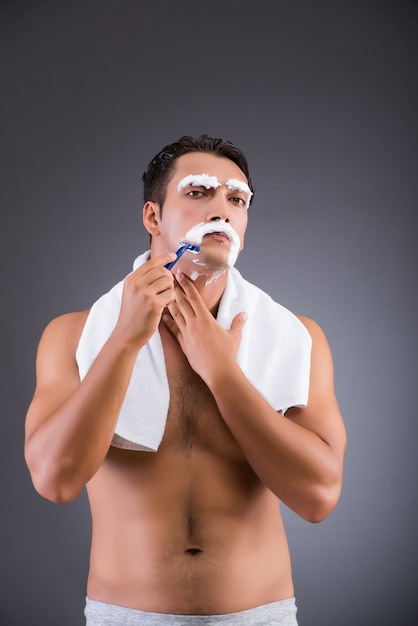 Man shaving on dark background